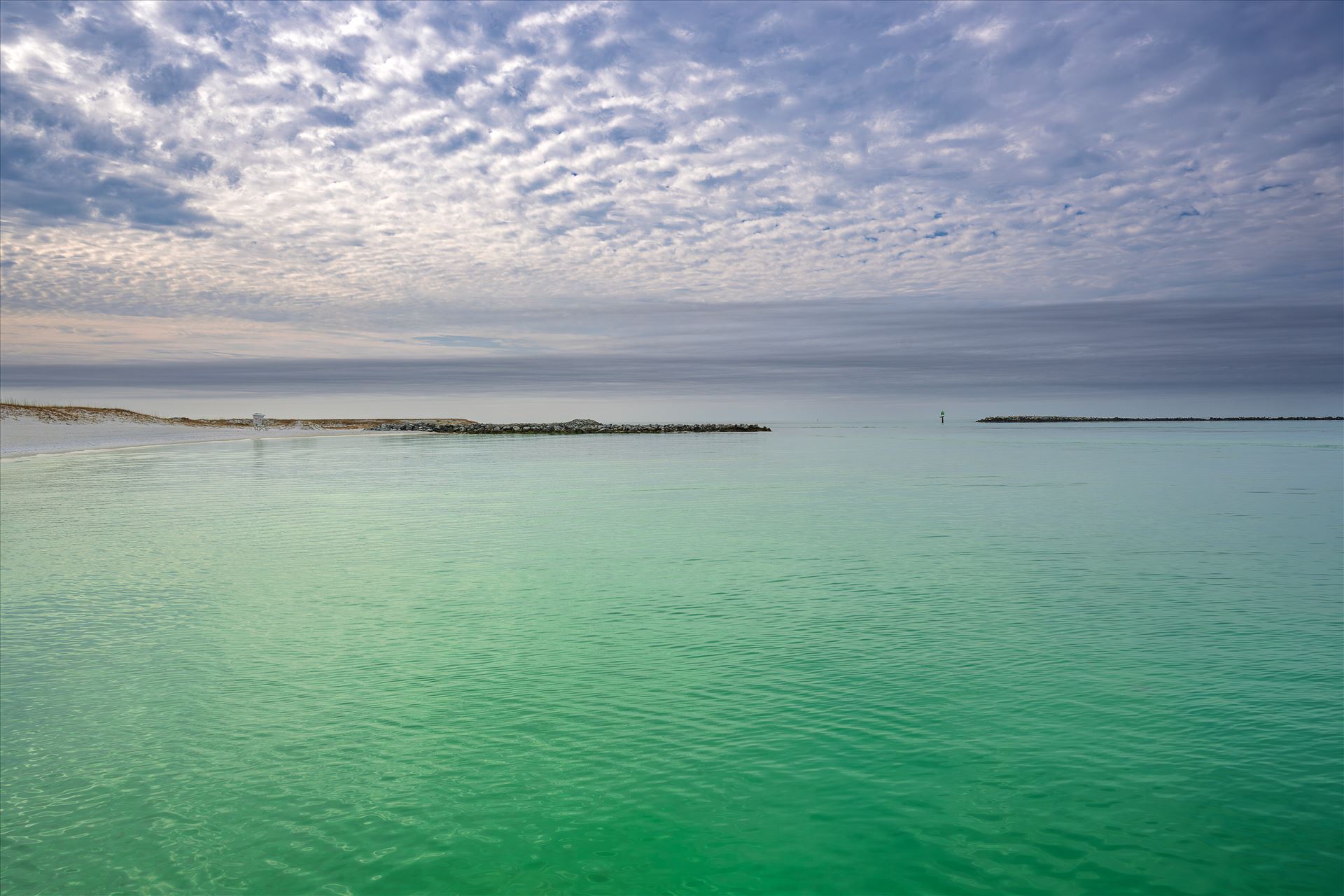 white sandy beach with emerald-green waters of Destin Harbor - A quiet moment on the coast, a white sandy beach with emerald-green waters of Destin Harbor, with a lifeguard stand standing watch beneath the open sky, ready for sunny days and salty breezes. by Terry Kelly Photography