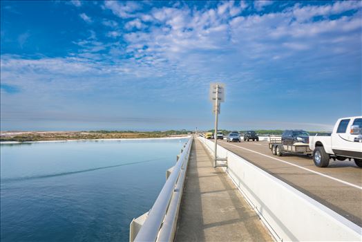 vehicle bridge with walking path blue sky blue water no people cars and trucks at destin harbor