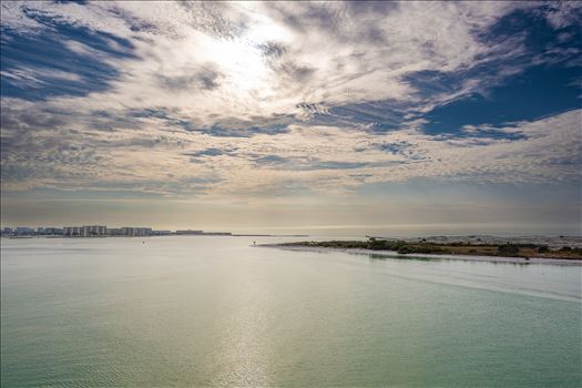 Destin Harbor Florida USA shines under a brilliant blue sky, with fluffy clouds reflecting on the emerald-green waters, creating a picture-perfect coastal scene.